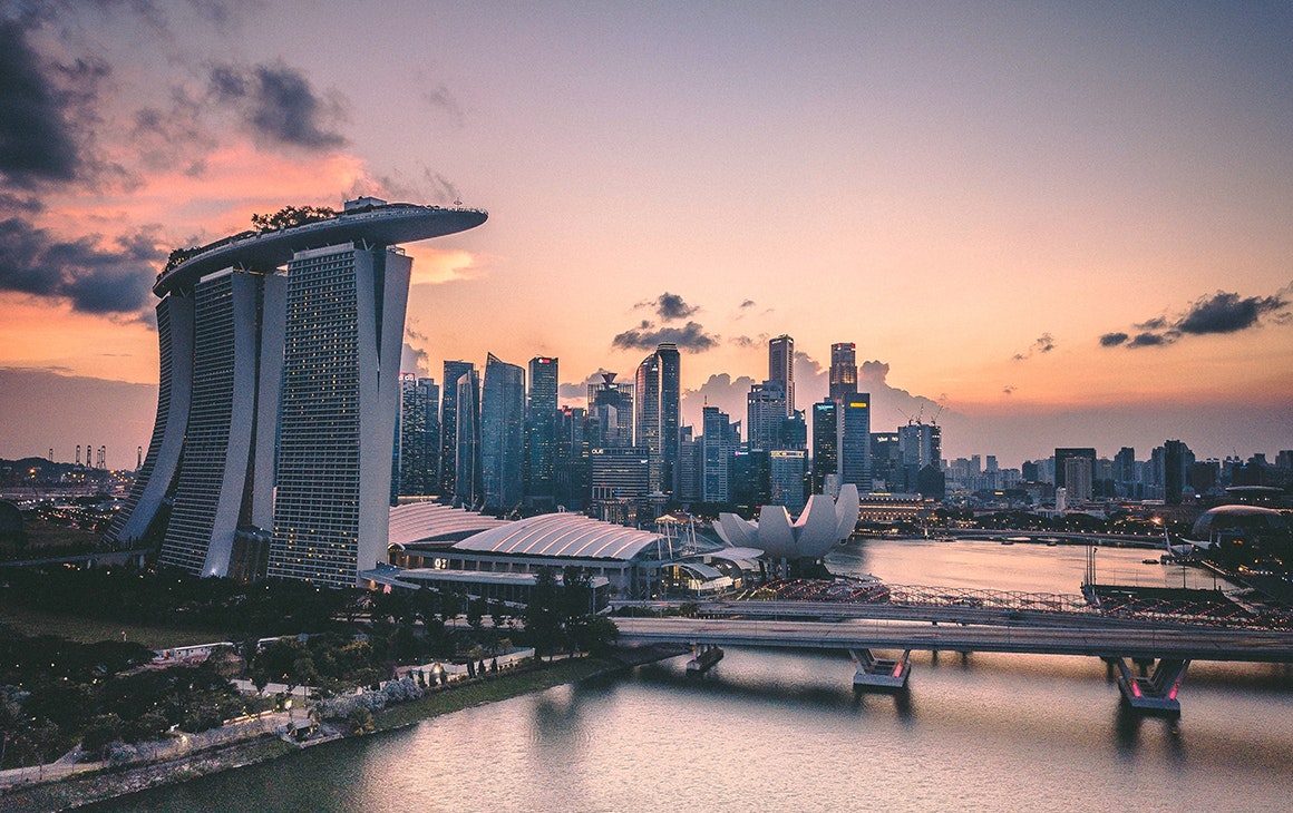 a cluster of building line an expanse of water in central Singapore at sunset.